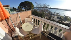A balcony with white chairs and a table, overlooking a body of water and a parking area. - Stunning apartment in Turanj with house sea view (Turanj)