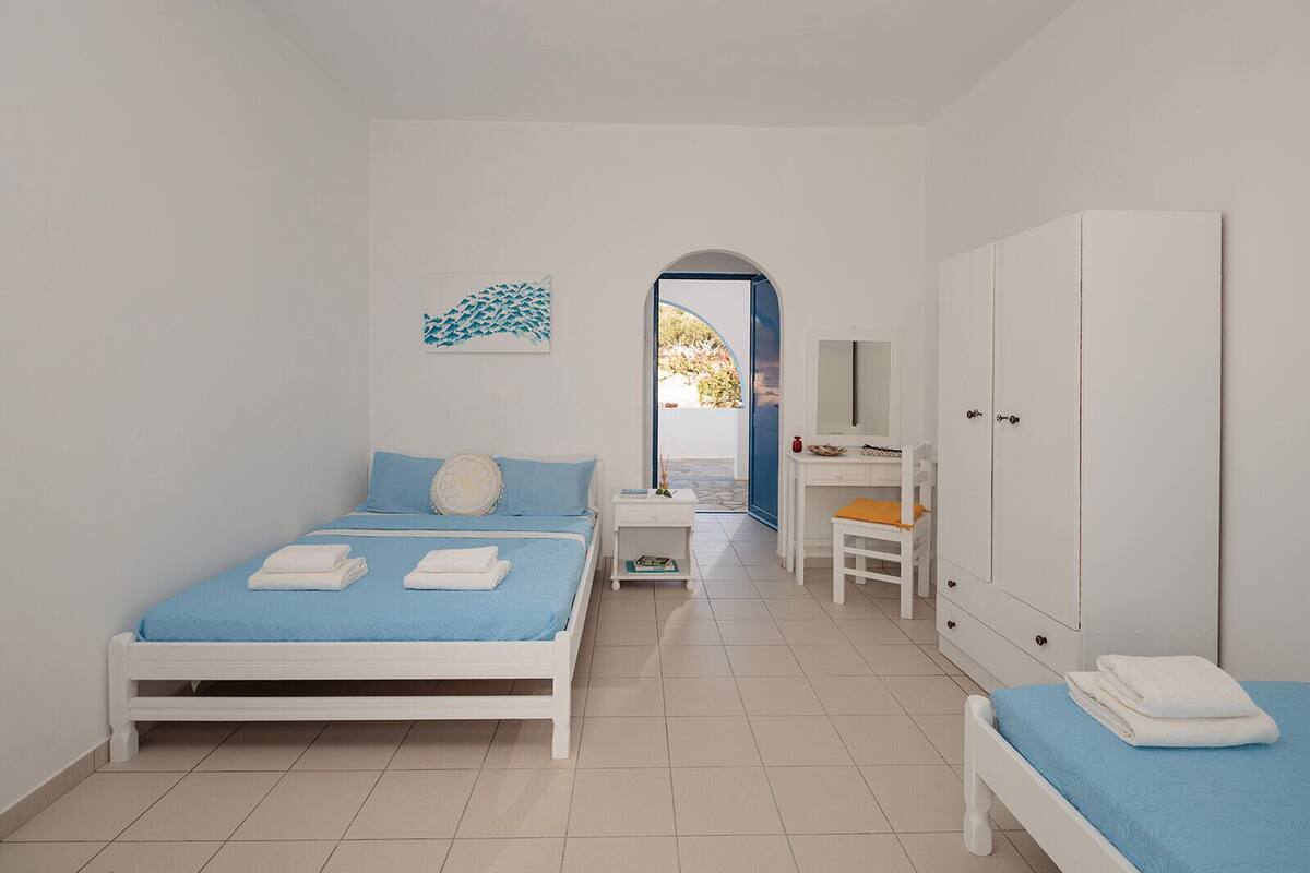 A bedroom with a bed, a desk, a wardrobe, and a small bathroom area.