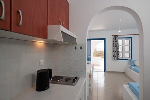 Een koelkast met diepvriezer, een kookplaat, kookgerei, borden en bestek