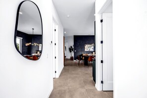 A modern interior with a hallway leading to a dining area, featuring a large mirror, dark walls, and a tiled floor. - Temple of Time- Stunning new modern home w/pool (Sarasota)