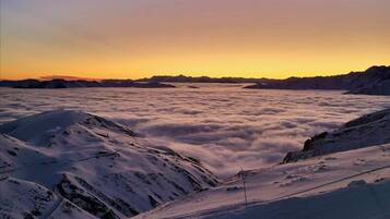 Paisagem montanhosa coberta de neve com céu claro ao pôr do sol.