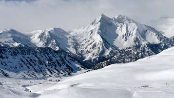 Een besneeuwd berglandschap met skipistes en een klein berghuis.