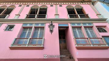 Un bâtiment rose doté de nombreuses fenêtres, de balcons et d’un escalier menant à l’entrée.