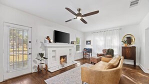 Ein Wohnzimmer mit Kamin, einer Couch, einem Fernseher und einem Deckenventilator.