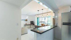 Une cuisine moderne dotée d’un îlot central, d’un coin repas avec un canapé et offrant une vue sur la ville grâce à de grandes fenêtres.