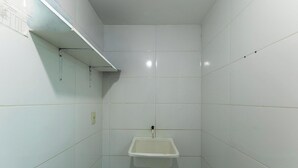 Une petite salle de bain carrelée, avec un seul lavabo et une étagère au-dessus.