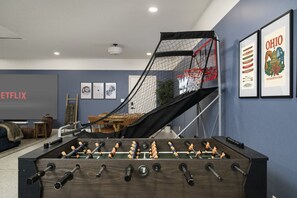 Une pièce avec une table de baby-foot, un téléviseur et des tableaux encadrés accrochés au mur.