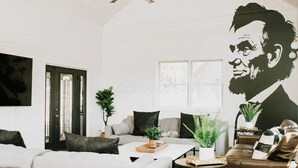 Uma sala de estar moderna com um sofá branco, uma mesa de centro e um mural grande na parede.
