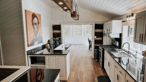Cozinha moderna com piso de madeira, armários brancos e uma ilha central.
