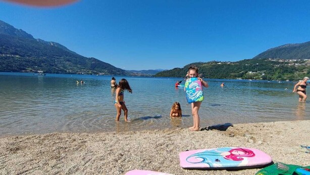 A lake with people swimming and standing in shallow water, surrounded by mountains. - Farmhouse in typical Trentino style, spacious, elegant, comfortable. (Civezzano)
