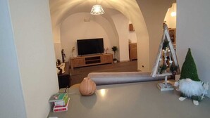 A living room with a curved ceiling, a flat-screen TV, a wooden coffee table, and a small Christmas tree. - Farmhouse in typical Trentino style, spacious, elegant, comfortable. (Civezzano)
