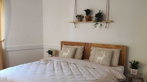 A bedroom with a large bed, wooden beams, a hanging plant shelf, and a small side table. - Farmhouse in typical Trentino style, spacious, elegant, comfortable. (Civezzano)