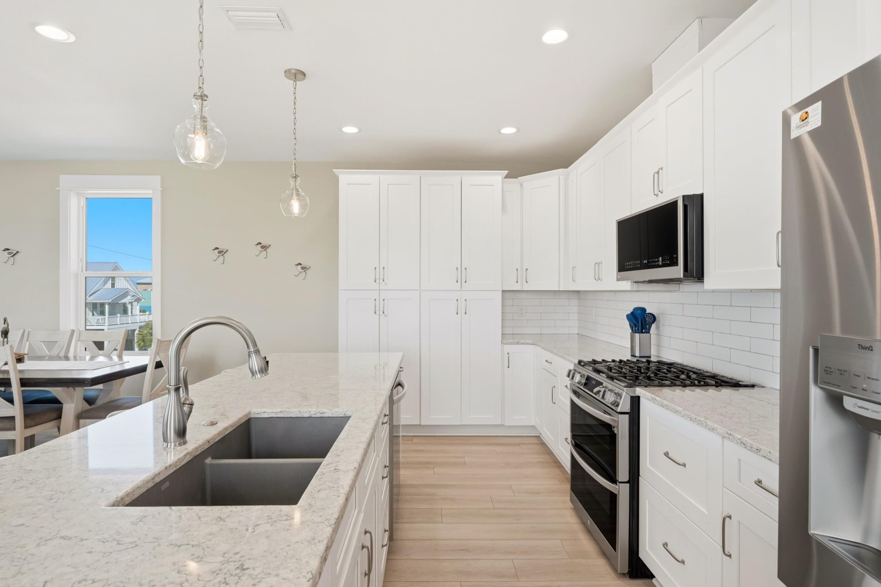 A modern kitchen with white cabinets, a stainless steel refrigerator, a built-in microwave, and a granite countertop.
