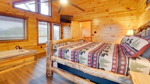 Un dormitorio tipo cabaña de troncos con una cama de madera, un banco y una ventana con persianas.