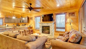 A cozy log cabin interior with a fireplace, wooden furniture, and a kitchen area. -  New Amazing View Cabin, 5 miles to Dollywood, 12 miles to Smokies, Sleeps 11 (Sevierville)