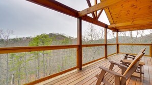 Una terraza de madera con una mesa y sillas, con vistas a un área boscosa.