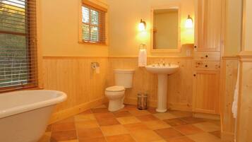 A bathroom with a bathtub, toilet, sink, and wooden walls.