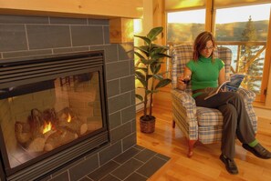 Una persona sentada junto a una chimenea con una planta a su lado.