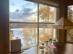 A room with a large window offering a view of a lake and trees.
