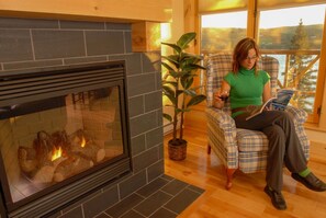 A person sitting by a fireplace with a plant beside them.