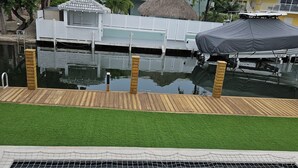 Ein Schwimmbecken mit Holzterrasse und einem strohgedeckten Gebäude.