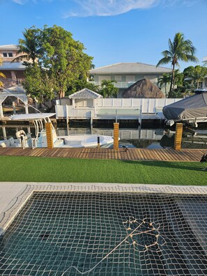 A swimming pool with a netted safety area, a wooden deck, and a thatched-roof structure. - Amazing 4 bedroom 4 bathroom home in Key Largo.  Great for families. Dock space (Key Largo)