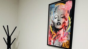 Une œuvre d’art encadrée accrochée au mur, un porte-manteau noir avec une serviette blanche, et un sol en marbre.