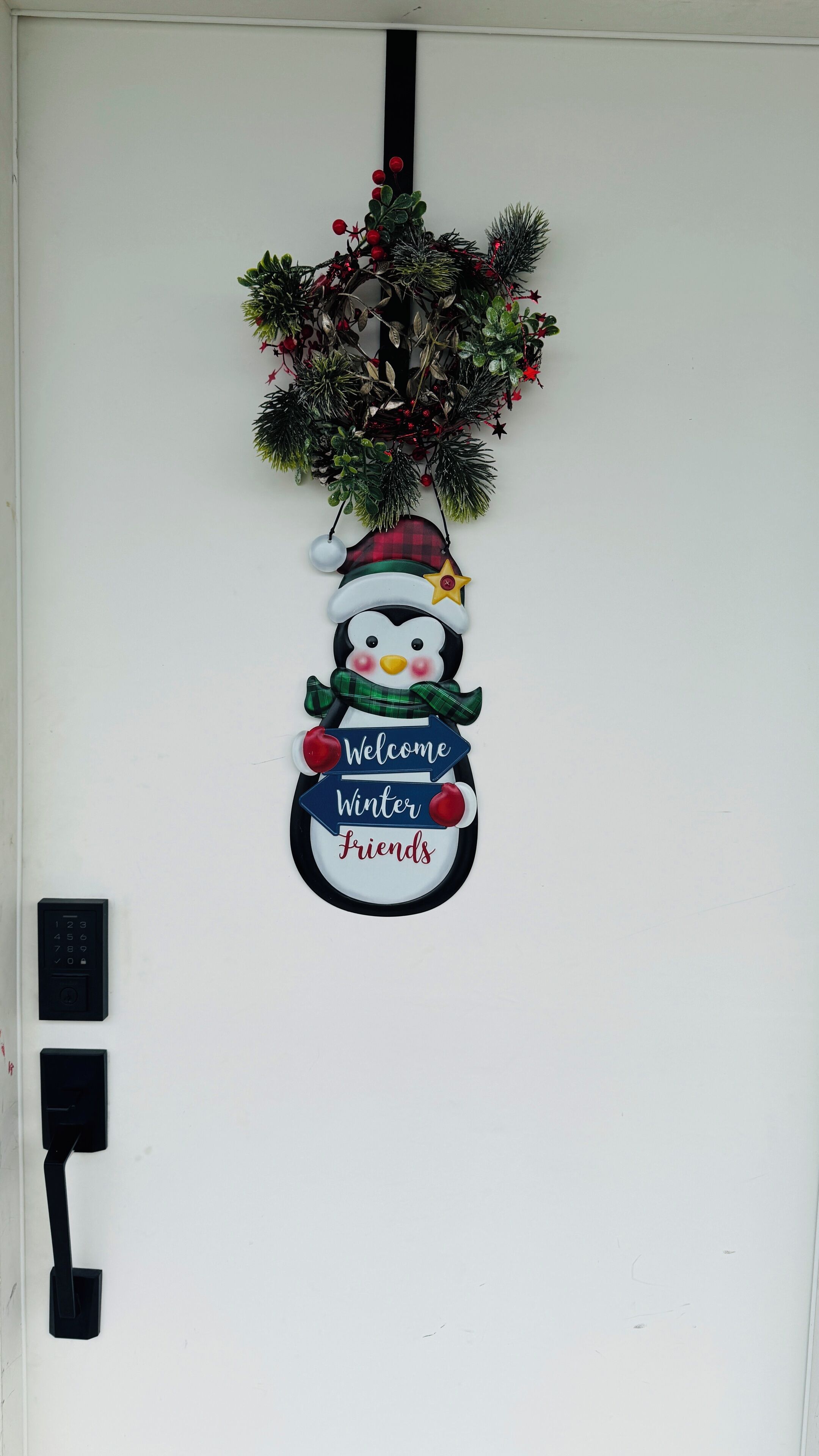 A door with a decorative wreath, a snowman sign, and a doorbell.