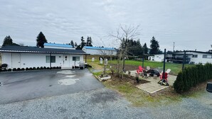 Un quartier résidentiel avec une maison blanche, une véranda et un espace barbecue.