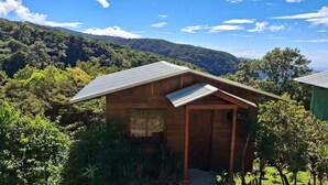 A wooden cabin with a sloped roof, surrounded by lush greenery and a mountainous backdrop. - villa sunset (Santa Elena)