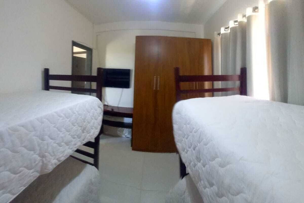 A bedroom with two single beds, a wooden wardrobe, and a door leading to another room.