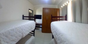 Un dormitorio con dos camas individuales, un armario de madera y una puerta que da a otra habitación.