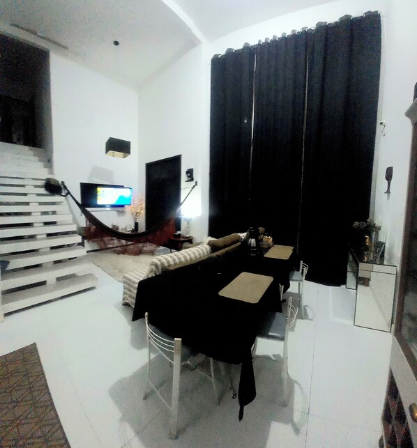 A room with a staircase, a bed, a desk, and a television. - Pousada Flor de Lis Homestay (Volta Redonda)