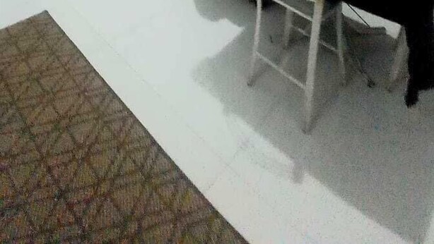 Uma sala de estar com sofá, televisão, mesa de centro e escada para um andar superior.
