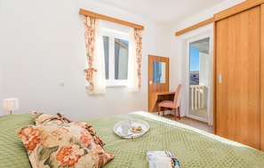 Ein Schlafzimmer mit Bett, Schreibtisch, Stuhl, einem Balkon und Blick ins Freie.