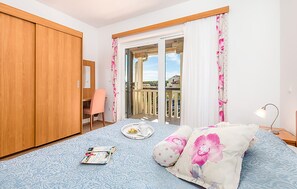 A bedroom with a bed, a desk, a chair, and a balcony with a view. - Amazing apartment in Palit with house sea view (Palit)