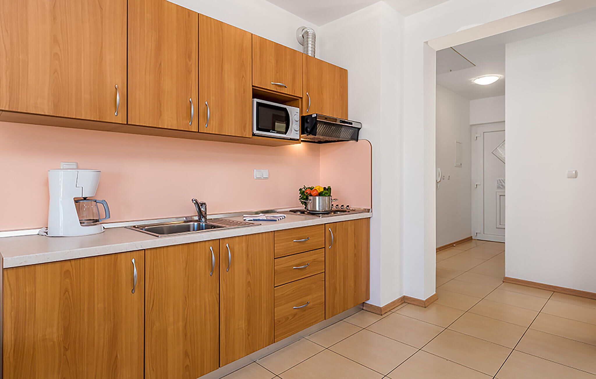 A modern kitchen with wooden cabinets, a microwave, a coffee maker, and a sink.