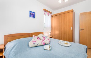 Un dormitorio con cama de madera, una mesita de noche, un armario de madera y una puerta.