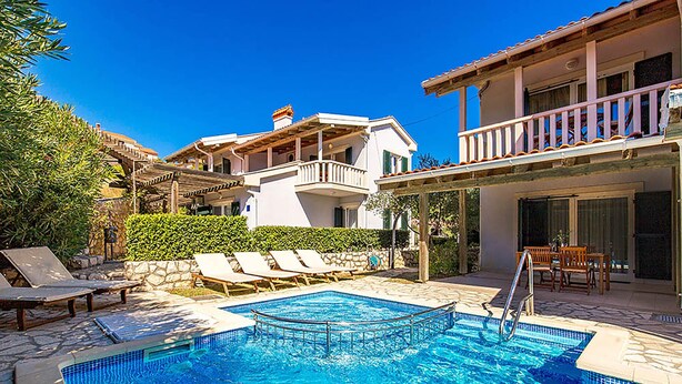 Un espace piscine comprenant des chaises longues, une piscine et un bâtiment doté de balcons.