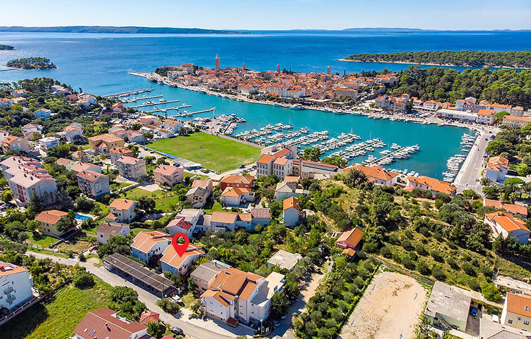 An aerial view of a coastal town with a marina, residential buildings, and a prominent tower.