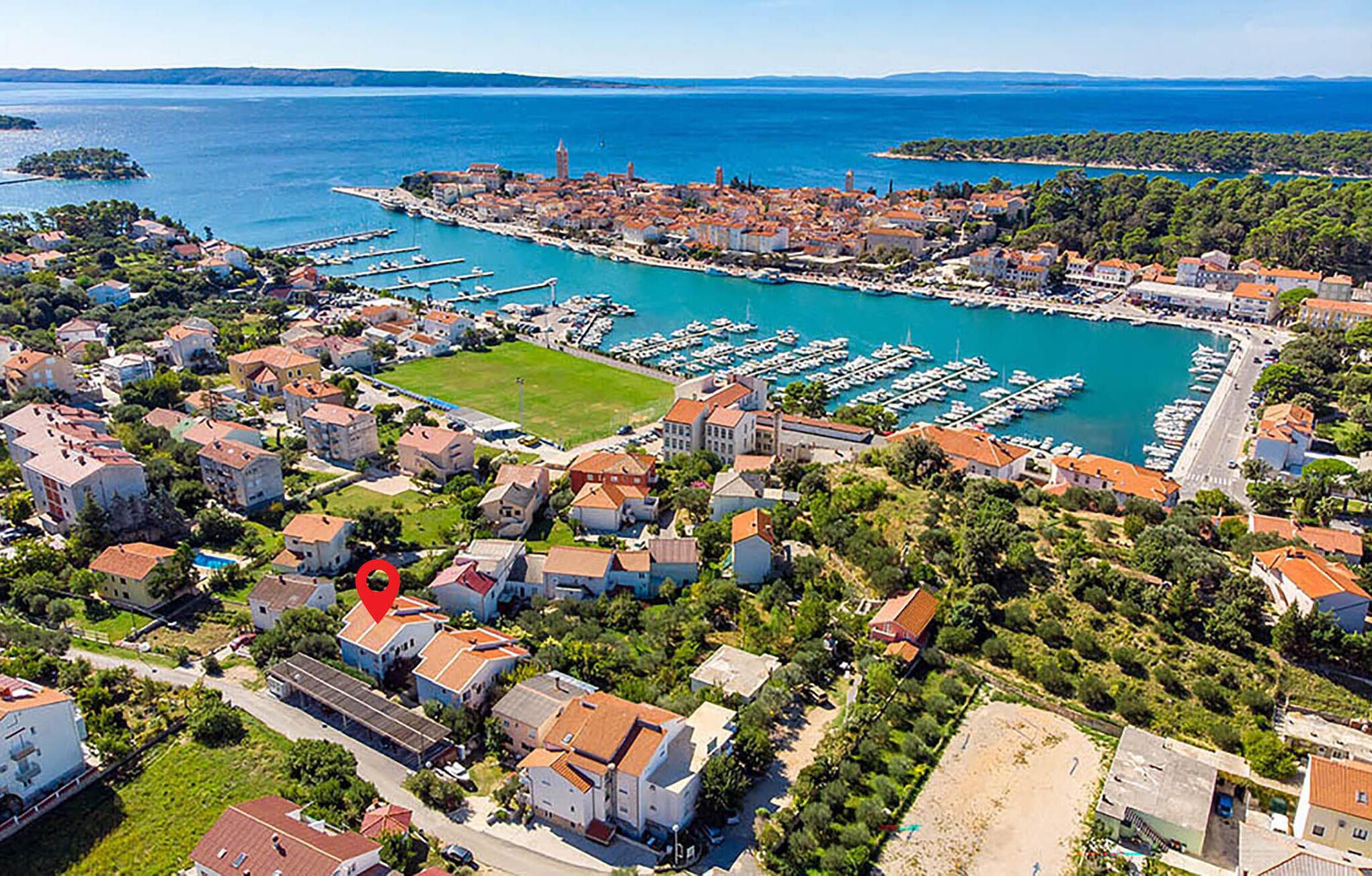 Vue aérienne d’une ville côtière avec un port de plaisance, des immeubles résidentiels et une tour imposante.