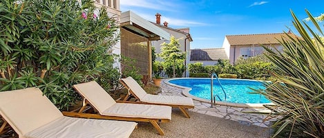 A pool area with lounge chairs and a clear blue sky.