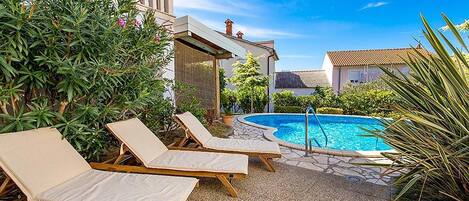 A pool area with lounge chairs and a clear blue sky.
