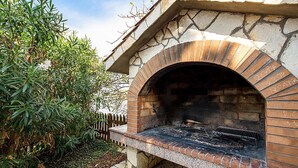 An outdoor brick oven with a stone arch, surrounded by greenery and a wooden fence. - Gorgeous apartment in Kampor with WiFi (Kampor)