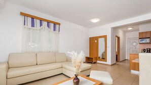 A modern living room with a beige sofa, a small table with a vase, and a kitchen area in the background. - Gorgeous apartment in Kampor with WiFi (Kampor)
