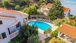 A residential property with a swimming pool surrounded by lounge chairs, a pergola, and a view of the sea. - Gorgeous apartment in Kampor with WiFi (Kampor)