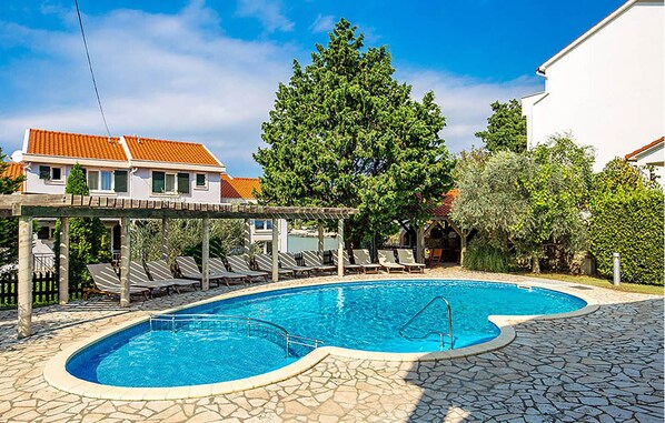 A swimming pool with a stone deck, lounge chairs, and a pergola. - Stunning home in Kampor (Kampor)