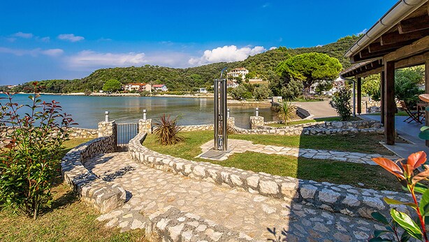 A stone pathway leading to a gazebo overlooking a lake, with houses and greenery in the background. - Nice apartment in Kampor (Kampor)