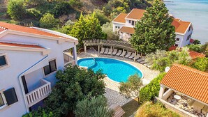 Ein Wohngebiet mit einem Schwimmbecken, umgeben von Liegestühlen und einer Pergola.