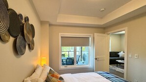 Ein Schlafzimmer mit einem großen Bett, einem Fenster mit Ausblick und einer Tür zu einem weiteren Raum.